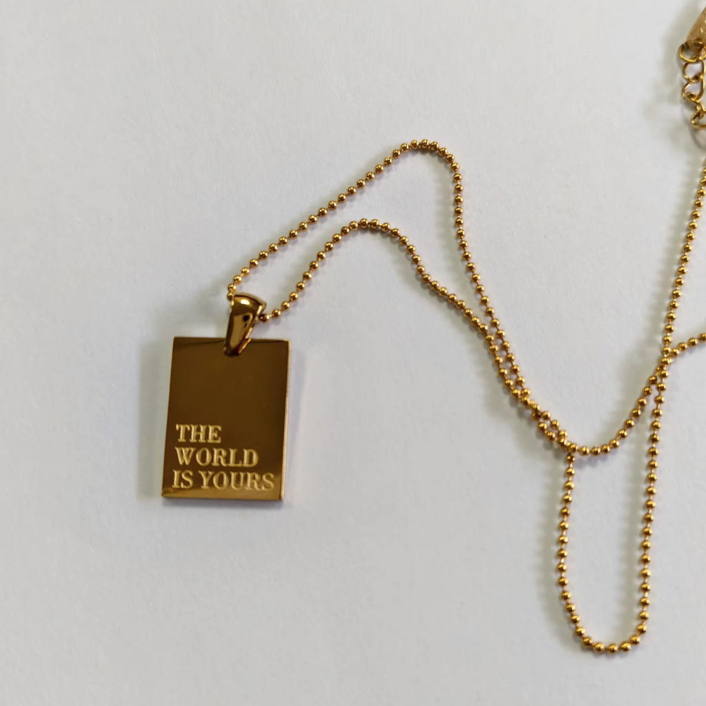 A rectangle dog tag with engraving in gold