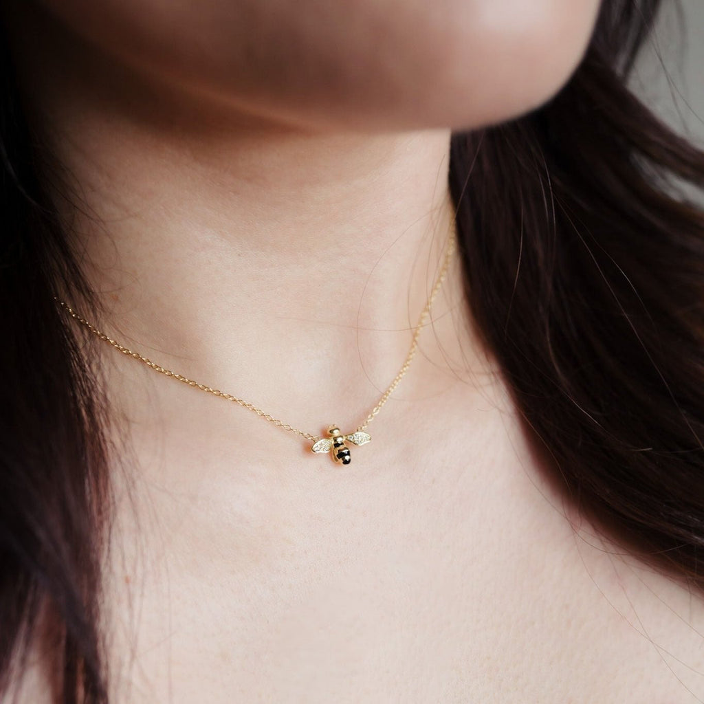 Dainty 14K gold necklace featuring a suspended bee pendant with black and cubic zirconia speckles on the wings