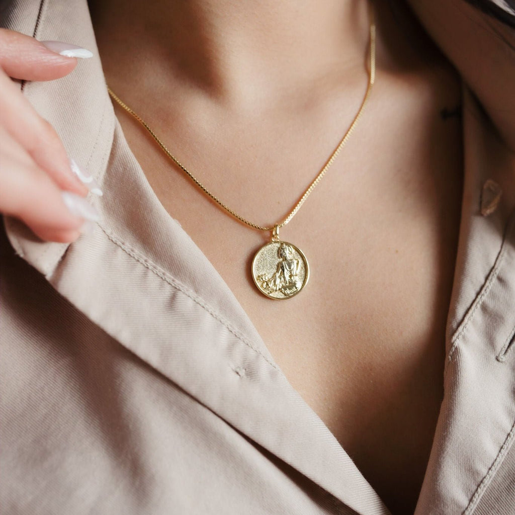 A stunning 14K gold necklace featuring a round pendant showcasing the image of Kuan Yin, the Buddhist goddess of compassion, with intricate details and a radiant golden shine.