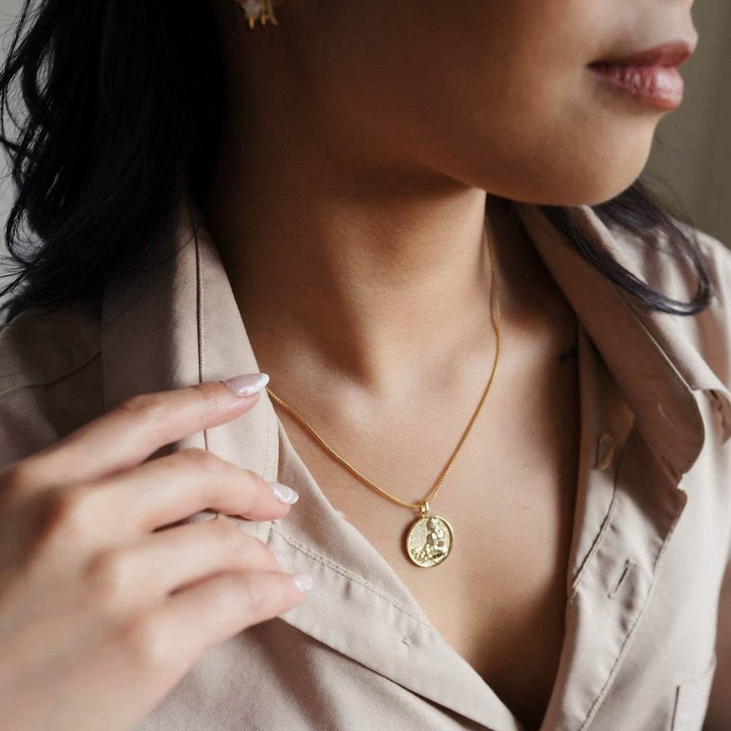 A stunning 14K gold necklace featuring a round pendant showcasing the image of Kuan Yin, the Buddhist goddess of compassion, with intricate details and a radiant golden shine.