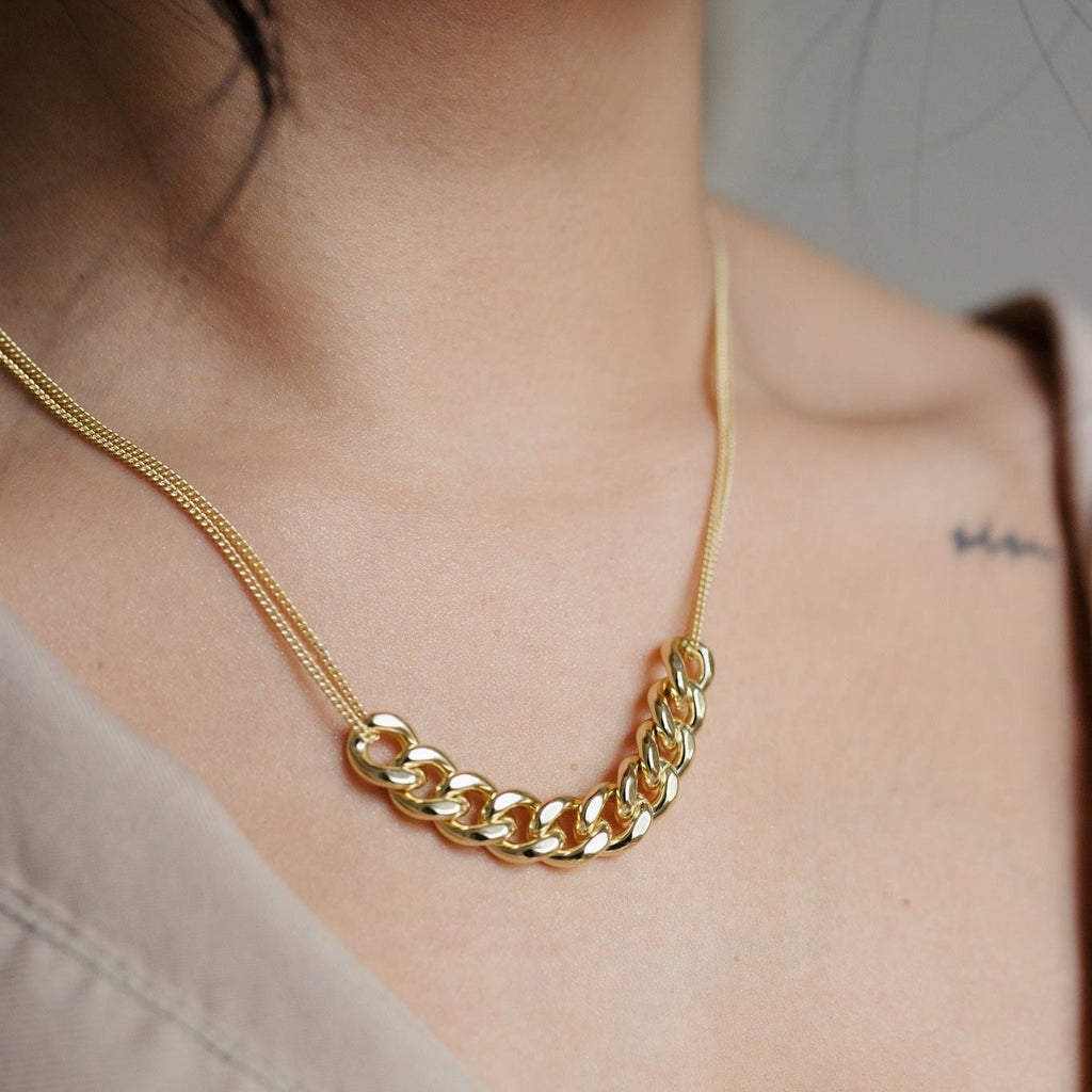 A stunning 14K gold necklace with double strands. The center of the necklace showcases ten larger link chains elegantly joined together, creating a bold and captivating focal point. The golden shine and intricate design make it a luxurious and eye-catching accessory.