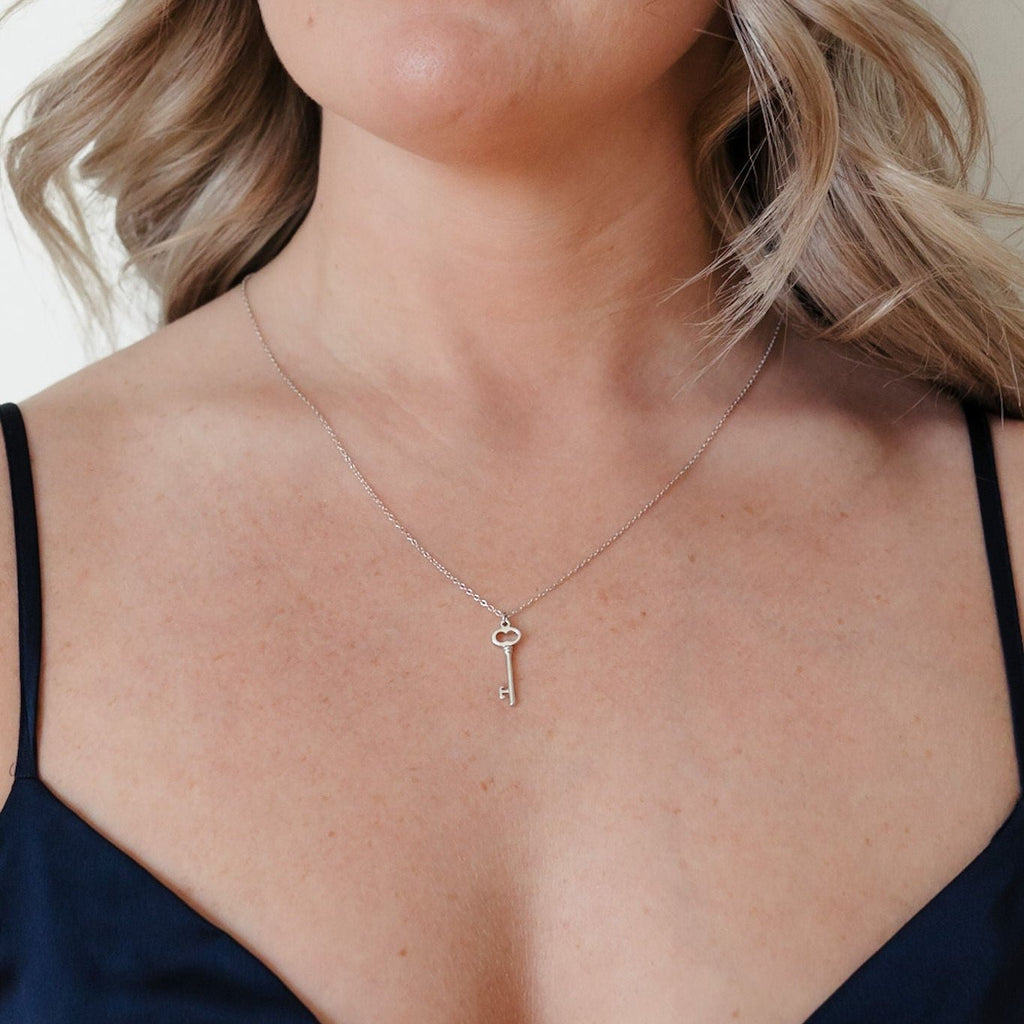 A stylish sterling silver necklace with a key-shaped pendant, designed by I Am Love Project. The pendant features intricate detailing and a sleek silver finish, creating an elegant and timeless accessory.