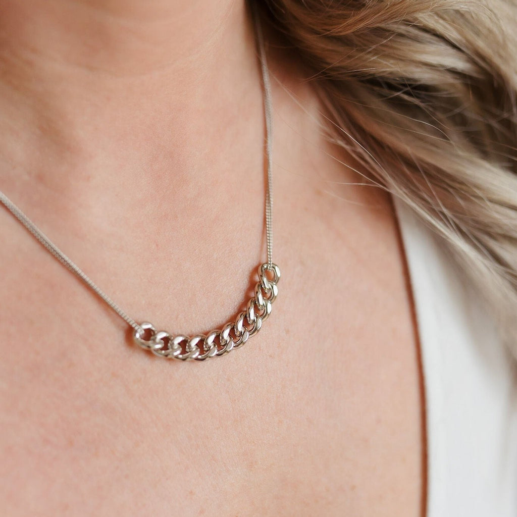 A striking sterling silver necklace with double strands. The center showcases ten larger link chains elegantly intertwined, creating a bold and stylish focal point. The sleek silver shine and intricate design make it a captivating and versatile accessory.