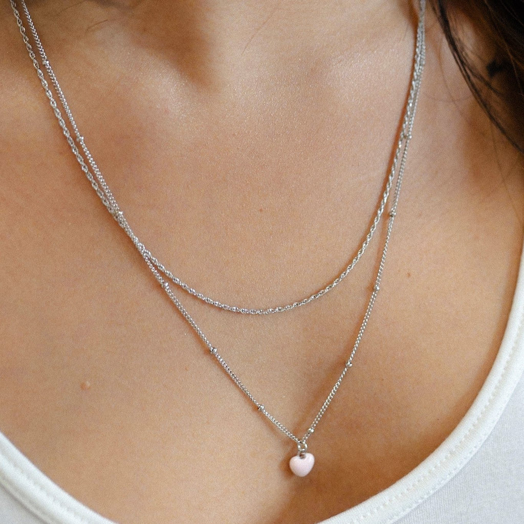 "Stylish rhodium plated sterling silver necklace with layered enamel pink heart, satellite, and rope chain, adding a touch of elegance and sophistication to your ensemble."